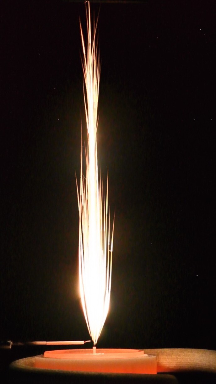 Bright particle-ignition plume above a glowing heating element